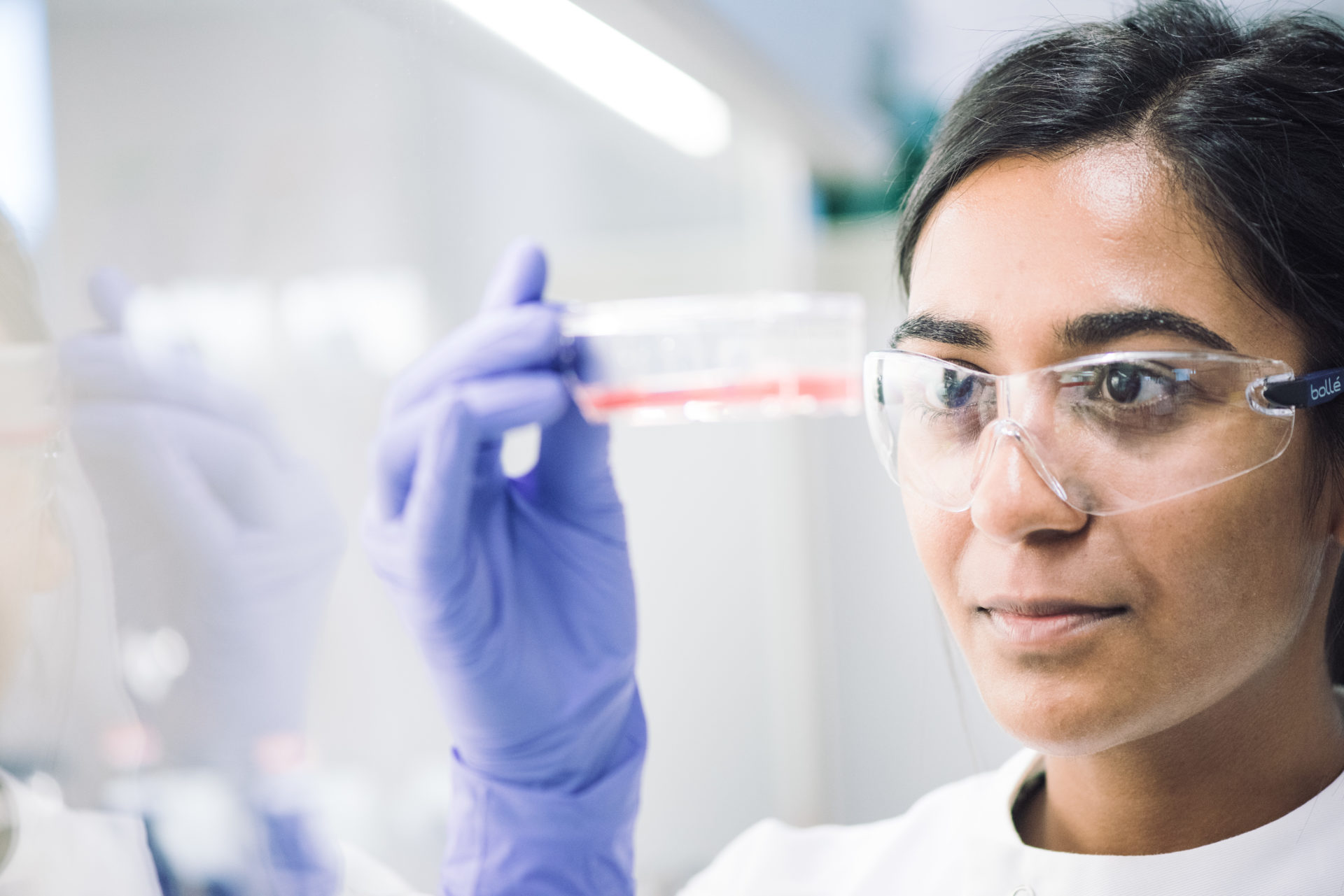 A scientist holding up an item and inspecting it